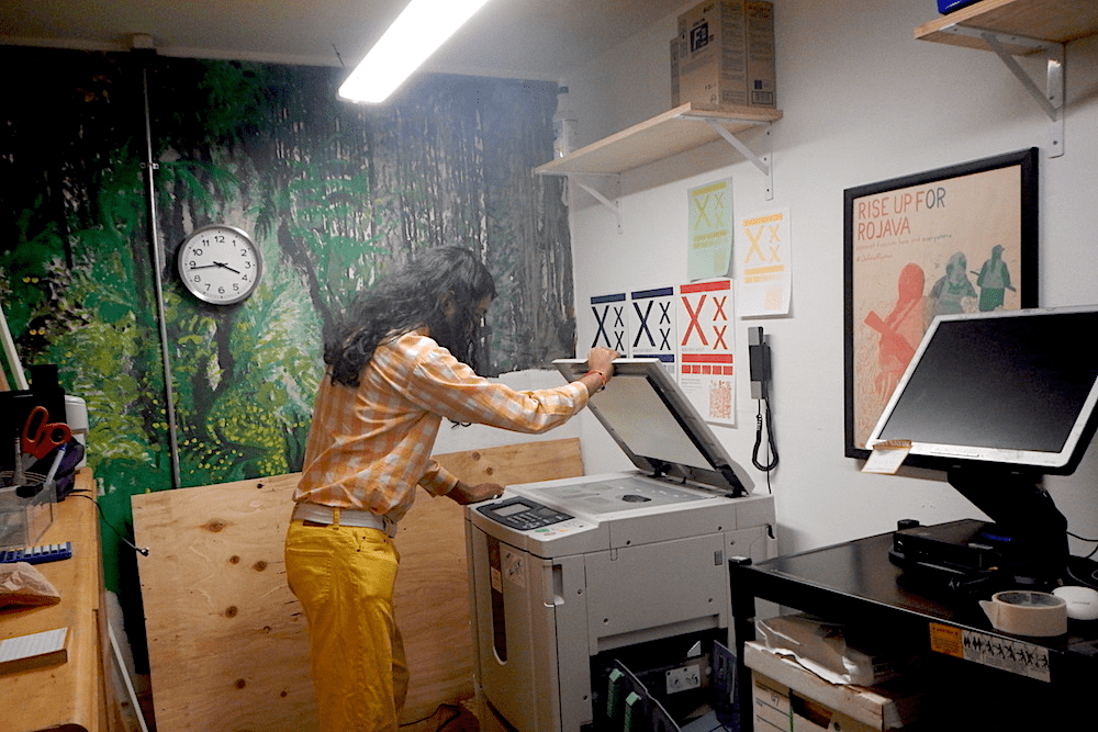Person with long hair opening lid of Riso machine to scan original